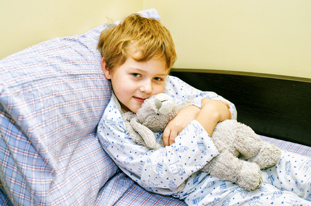 boy in bed with a stuffed animalの写真素材