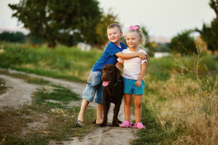 Two children walking with a dog breed Labradorの写真素材