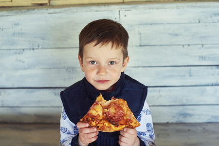 boy holding a slice of pizzaの写真素材