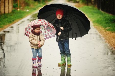 children walk in the rain holding umbrellasの写真素材