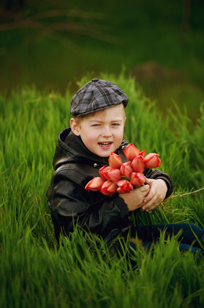 The boy on the lawn in spring with a bouquet of flowers . Spring gift .の写真素材