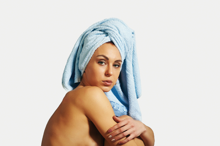 Portrait of a girl in a towel in the bathroom. Cosmetics and body careの写真素材