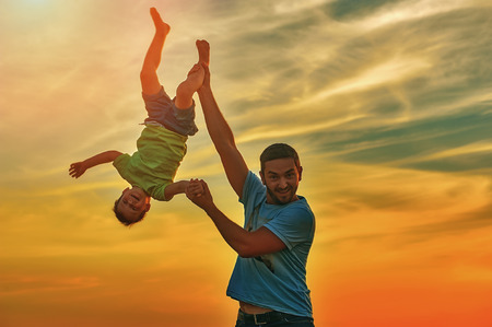 Happy father playing with son on sunset background .The concept of father's dayの写真素材