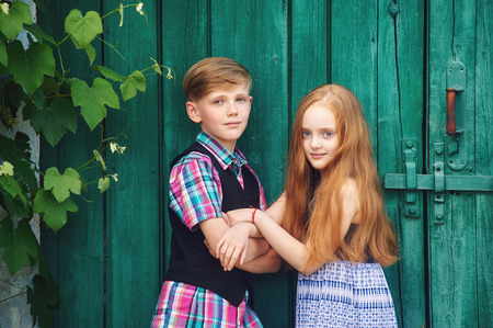 Beautiful , fashionably dressed children at an old vintage door.The concept of children's friendshipの写真素材
