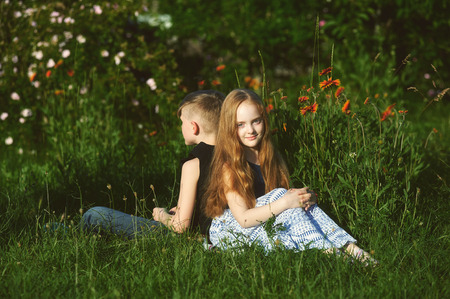 boy and girl sitting on grass back to each otherの写真素材