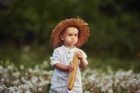 the boy in the box at the loaf of bread in a white dress and straw hatの写真素材