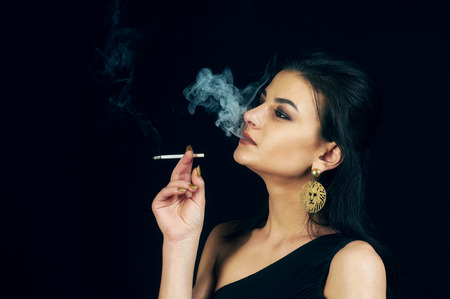 woman Smoking cigarette on a black background .の写真素材