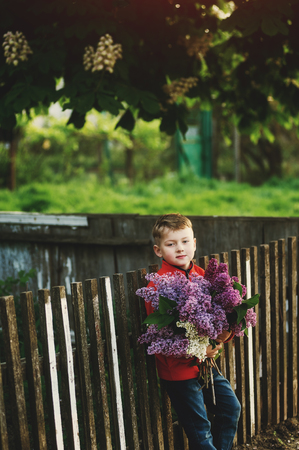 Portrait of a boy with a bouquet of lilacs . Dressed child holding a bouquet of flowers of lilacの写真素材