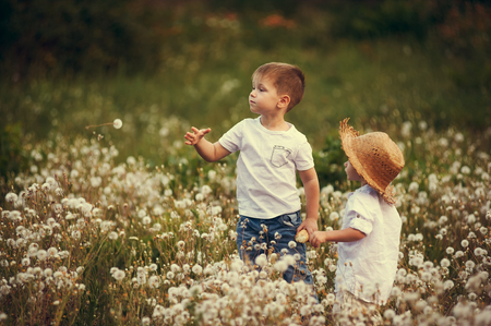 Children walking in a field. Brothers on a summer walk in the white robesの写真素材