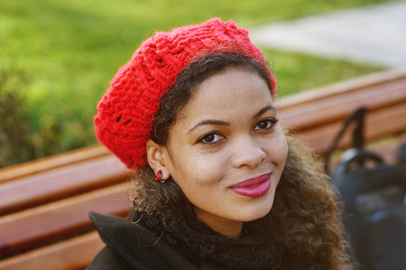 a young colored woman in the city .A woman in a red knitted beret on the streetの写真素材