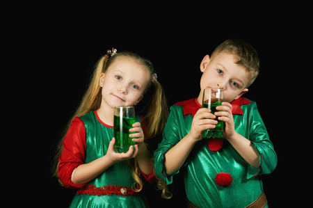 Cheerful children in green suits with a glass of green drink on St. Patrick's dayの写真素材