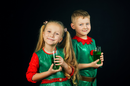 Cheerful children in green suits with a glass of green drink on St. Patrick's dayの写真素材