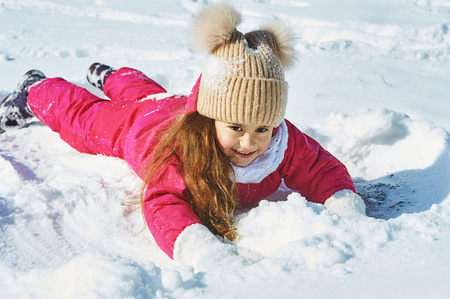 Happy baby on a winter walk .Little girl having fun playing with snowの写真素材