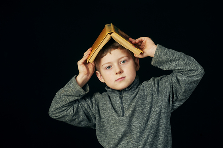 Tired boy holding a book over his head.The concept of pre-school educationの写真素材