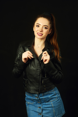 Young woman in leather jacket and denim skirtの写真素材