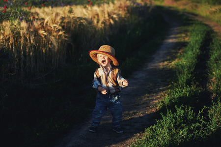 Cheerful kid on a summer walk . Boy on the dirt roadの写真素材