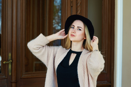 close-up portrait of a young beautiful fashionable woman posing on the street. Model in a stylish...