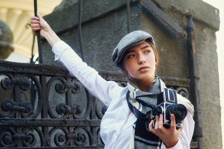 Girl photographer with an old camera in his hands .Stylish fashionable girl photographer in the city streetの写真素材