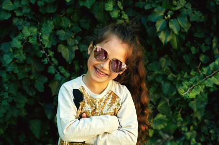 Adorable baby wearing sunglasses sitting on a green grass