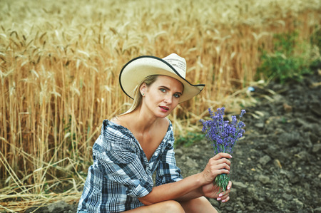 Young woman in casual clothes for a walk in the field with wheat .Girl holding a flowering lavender