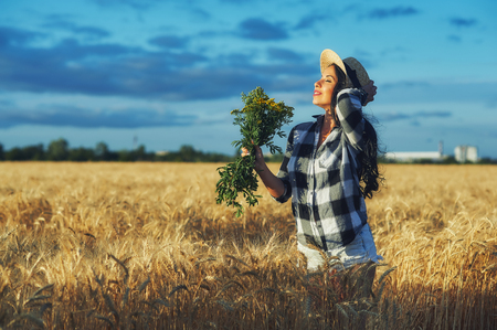 Young woman in straw hat in nature .Girl holding wildflowersの写真素材