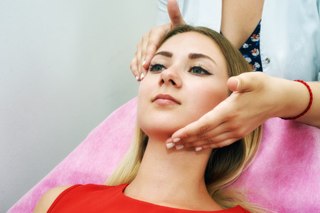 The girl doing the facial massage . Young beautiful woman on cosmetic procedures .の写真素材
