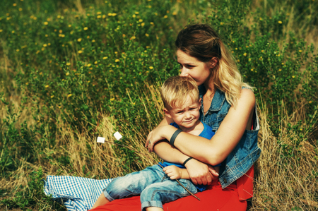 A young mother is resting with her son on a country walkの写真素材