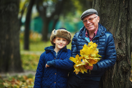 Grandson and grandfather on a walk in the autumn Park. Family valueの写真素材