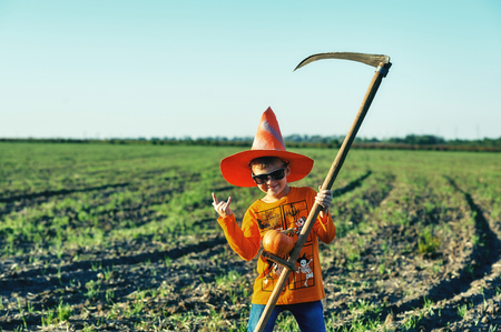 Halloween. Cheerful boy with a scythe in nature. Cheerful holidayの写真素材