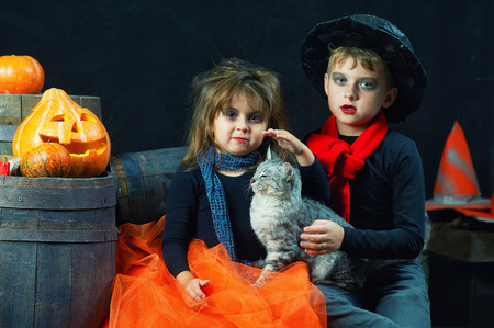 brother and sister on Halloween. Funny kids in carnival costumes on dark background . Funny kids and pumpkinsの写真素材
