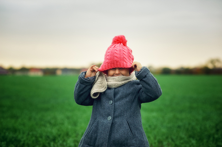 Portrait of a little girl on an autumn walk . The child in a coat and hat . The concept of children's clothingの写真素材