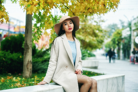 Portrait of a young woman on the streets of the autumn city . A girl in a wide-brimmed felt hat and a light coatの写真素材