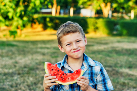 Portrait of a boy with a watermelon . The child is holding a slice of ripe watermelonの写真素材