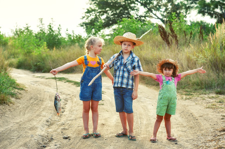 children go fishing, a group of children with a fishing rod and caught river fish on the road