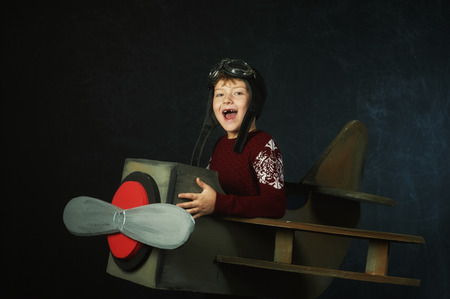 Little child playing airplane pilot, boy playing with airplane on dark backgroundの写真素材