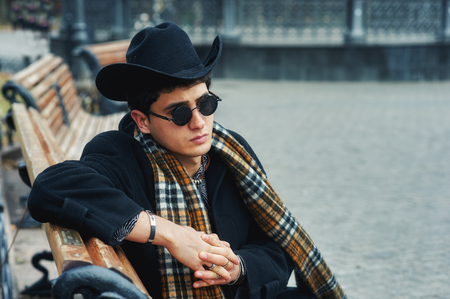 portrait of a stylish man on the street . man in black coat, plaid scarf and hatの写真素材