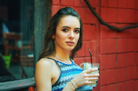 Portrait of a young woman with a glass of soft drink in a cafeの写真素材
