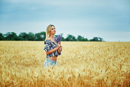 Young woman with a bouquet of lavender for a walk in the fieldの写真素材