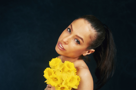 Portrait of a young beautiful girl with flowers in the Studio . The concept of female beauty and attractivenessの写真素材