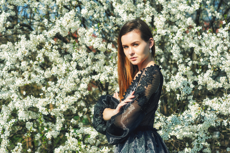 Portrait of a young beautiful fashionable woman in an evening dress . Girl posing in a blooming gardenの写真素材