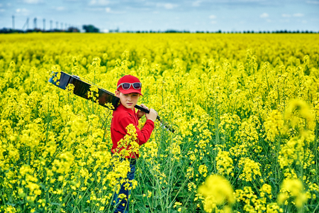 Portrait of a boy with an acoustic guitar in a yellow field . Young aspiring musicianの写真素材