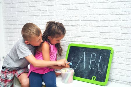 The child learns the letters. Older brother teaches sister alphabet. Outside school educationの写真素材