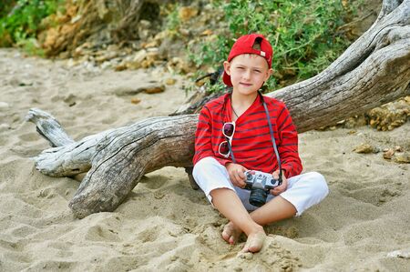 Fashionable handsome boy on a summer walk . Rest and travel . Child posing with an old cameraの写真素材