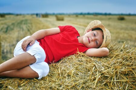Portrait of a little boy on vacation in the field . The child lying in the mangerの写真素材