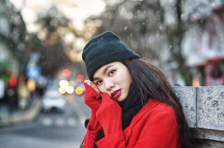 Young woman on a winter day in the city .  Girl in a hat and a red warm coatの写真素材