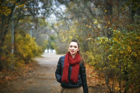 Portrait of a young beautiful woman in the autumn Park . The girl in the red scarfの写真素材