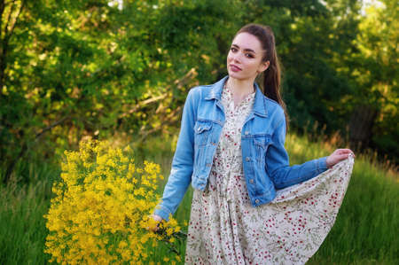 Portrait of a young woman in a denim jacket in nature. Girl on a country walkの写真素材