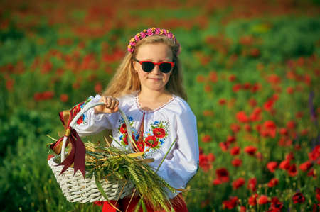 Portrait of a girl in national costume in a field with poppies