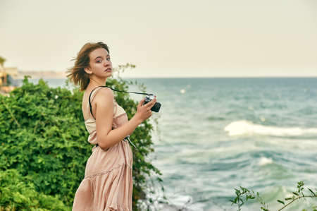 A young girl in a retro dress is relaxing on the sea coastの写真素材