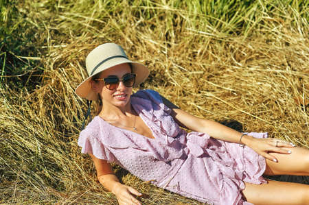 Portrait of a young beautiful woman in a summer dress and a straw hat in natureの写真素材